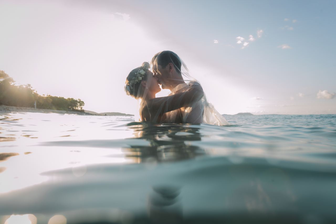 Wedding couple kissing in the water at sunset